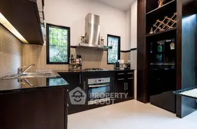 Modern kitchen with sleek dark cabinetry, stainless steel appliances, and ample natural light.