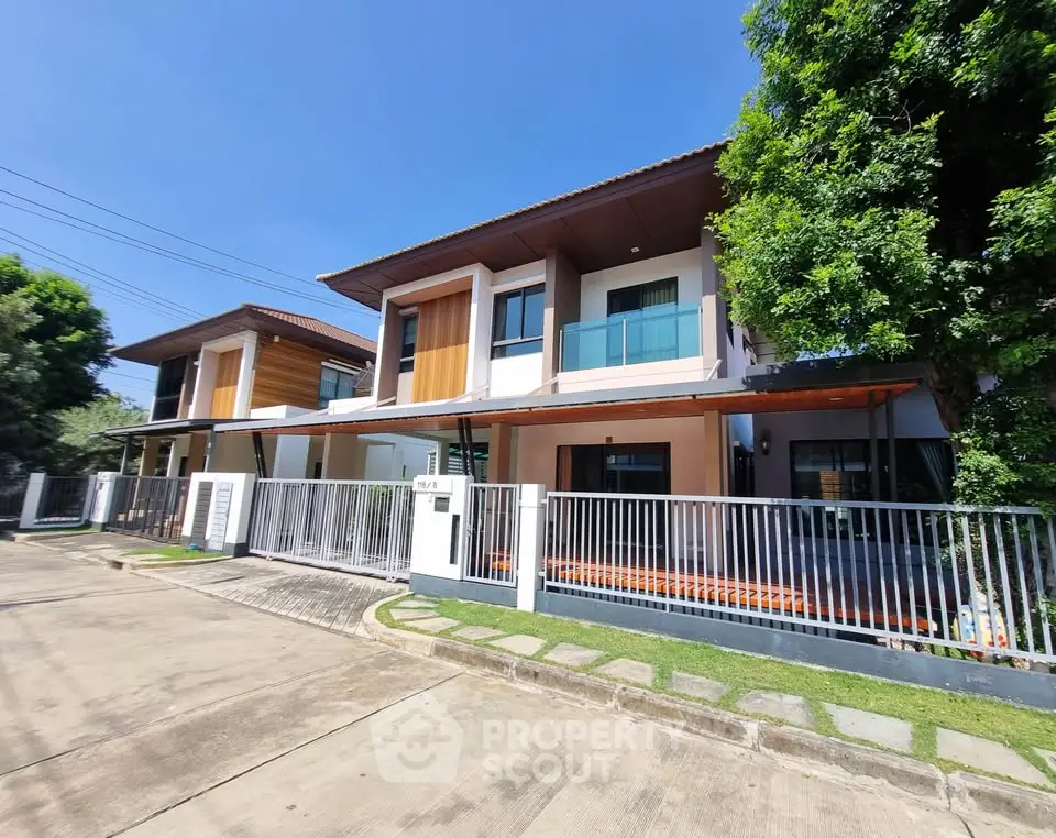Modern two-story house with spacious balcony and lush greenery
