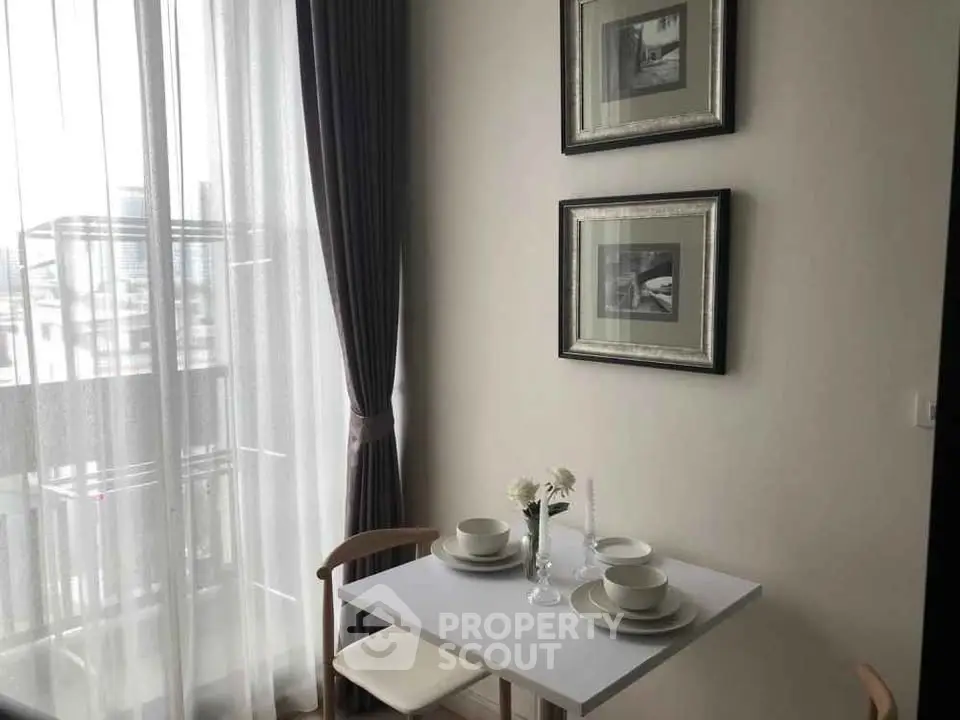 Cozy dining nook with elegant tableware and framed art by a sunlit window.