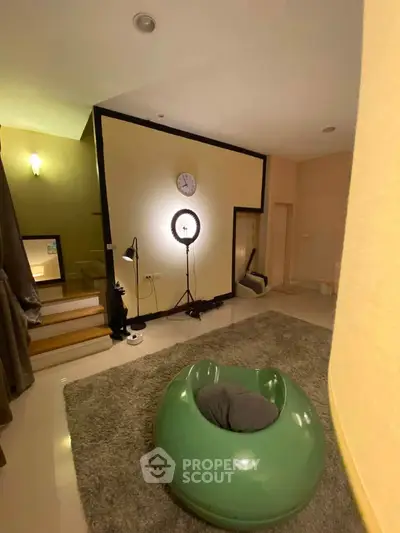 Modern living room with unique green chair and stylish lighting, perfect for cozy relaxation.