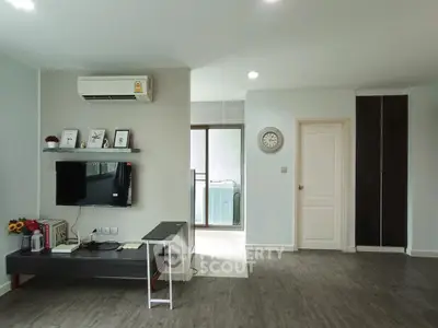 Modern living room with air conditioning and stylish decor, featuring a wall-mounted TV and sleek flooring.