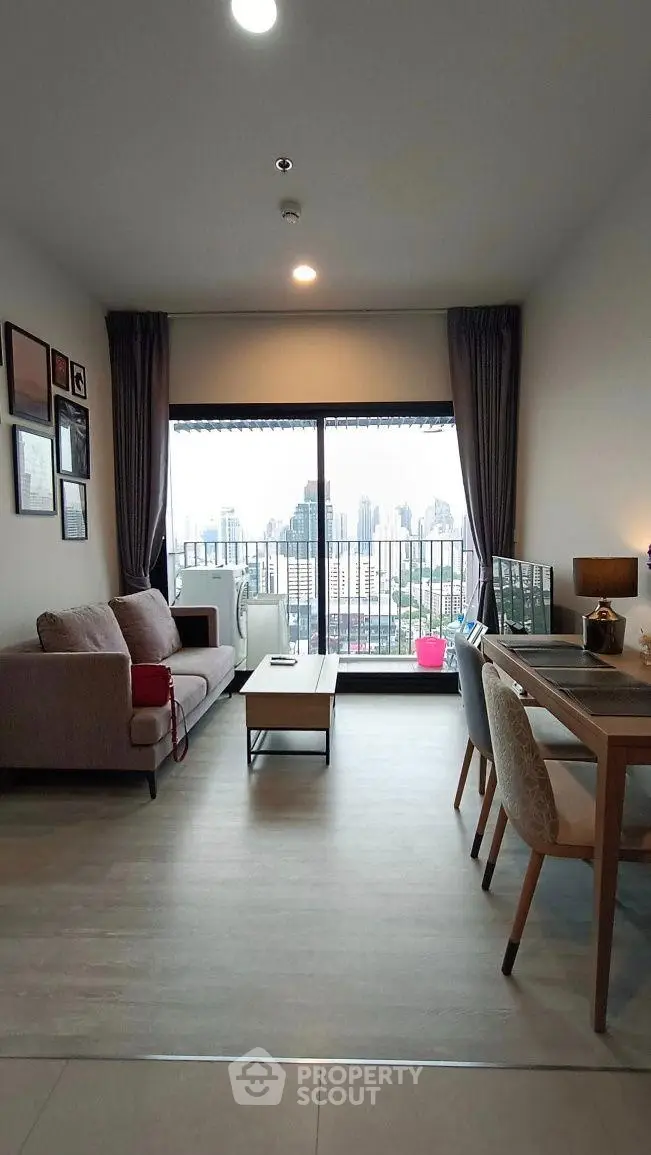 Modern living room with city view, stylish furniture, and large windows in a high-rise apartment.