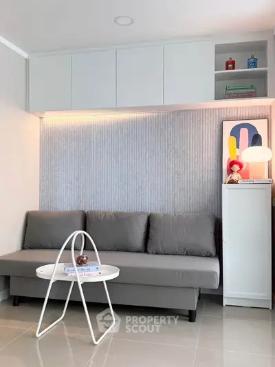 Modern living room with sleek gray sofa, stylish wall decor, and minimalist white furniture.
