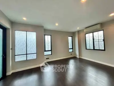 Spacious modern living room with large windows and dark wood flooring