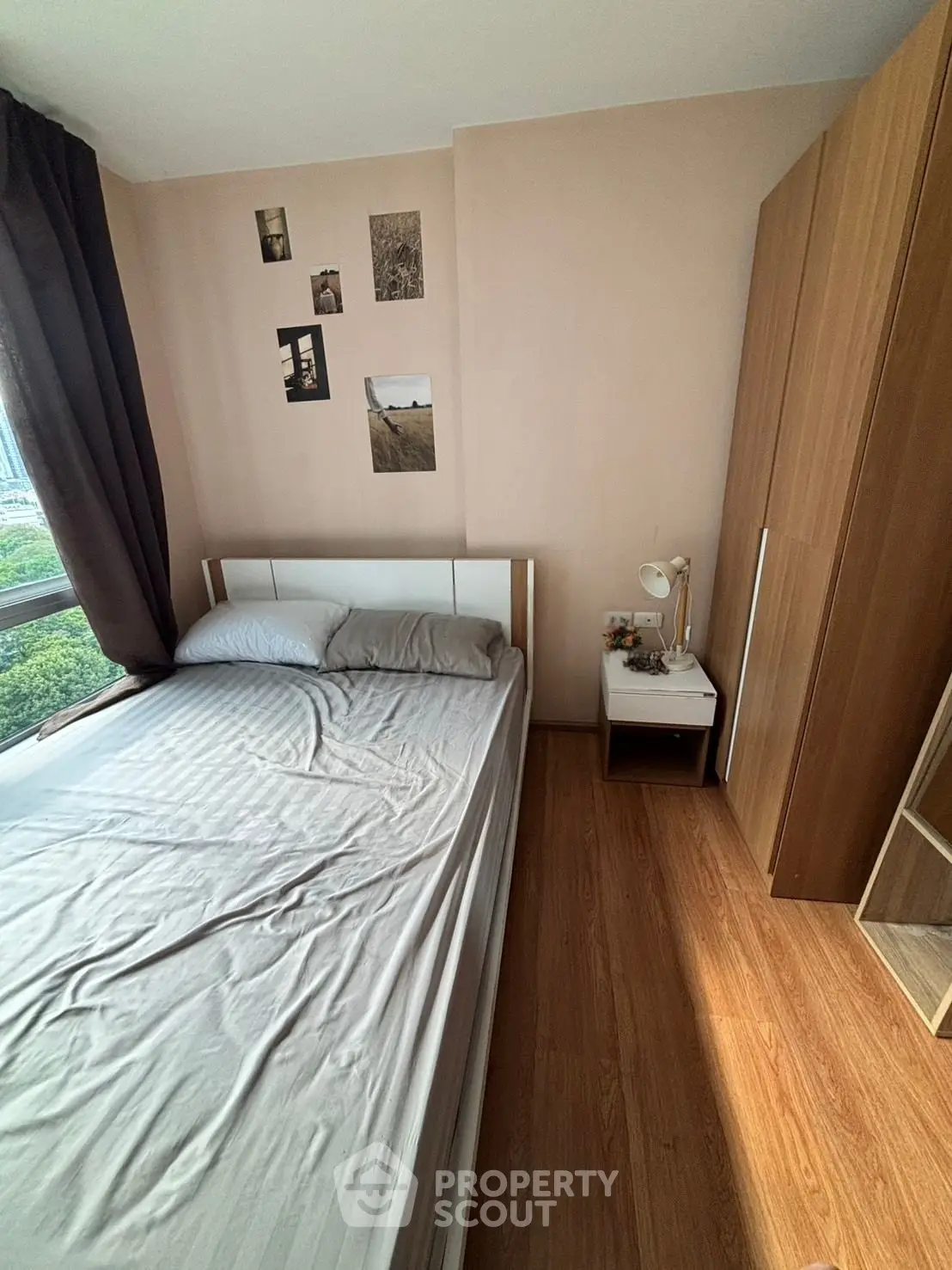 Cozy bedroom with wooden flooring, large window, and modern decor in a stylish apartment.