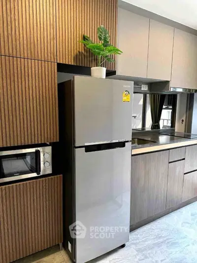 Modern kitchen with sleek cabinets and stainless steel fridge in stylish apartment.