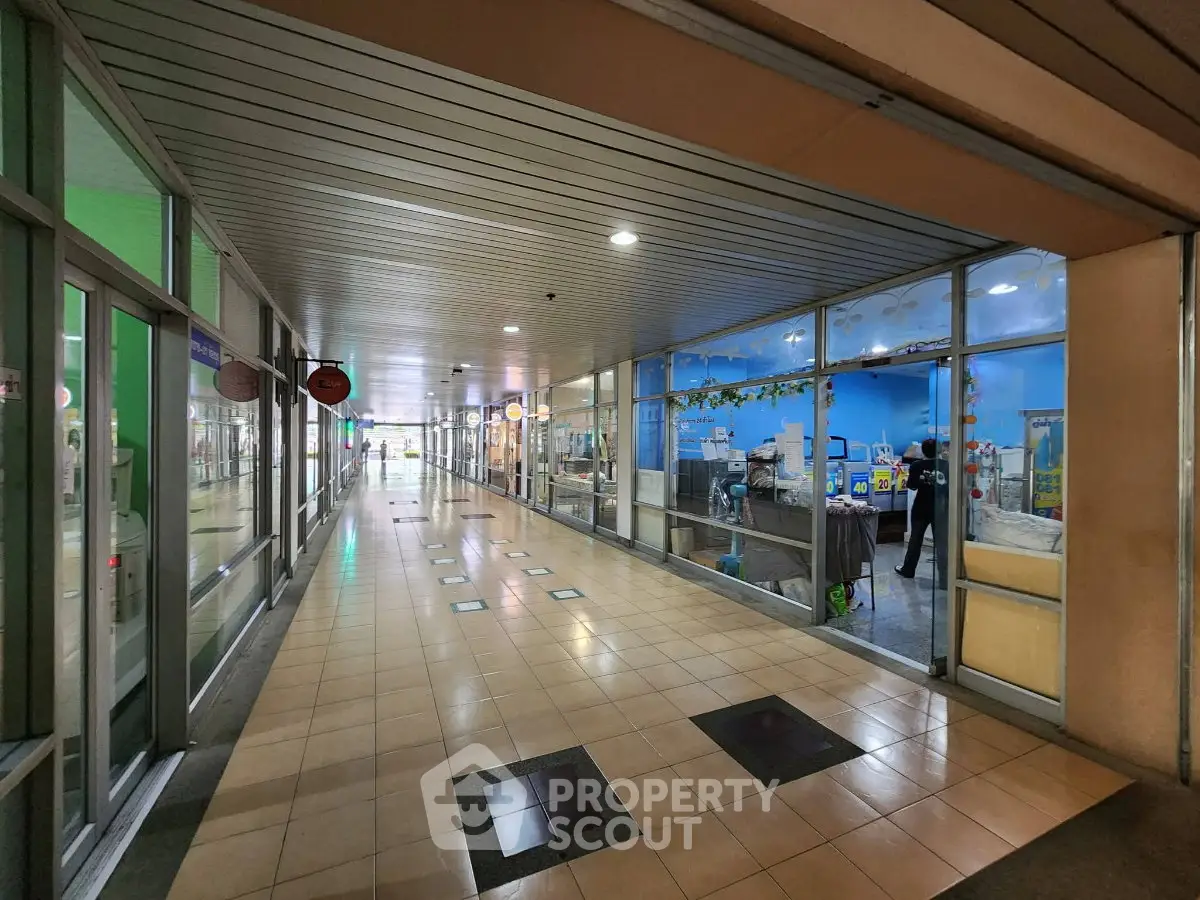 Spacious commercial corridor with glass storefronts and tiled flooring, ideal for retail businesses.