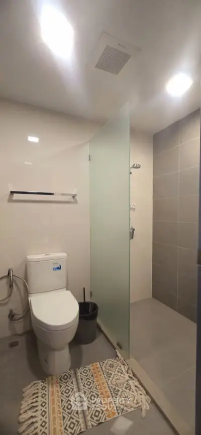 Modern bathroom with glass shower and sleek fixtures in contemporary apartment.