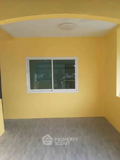 Bright yellow exterior with window and tiled floor, perfect for cozy outdoor space.