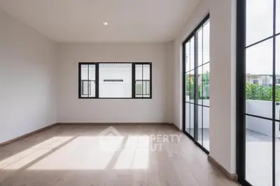 Spacious empty room with large windows and wooden flooring, perfect for customization.