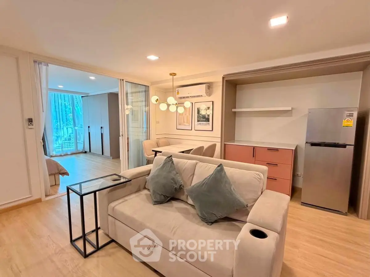 Modern living room with cozy sofa, stylish lighting, and open layout leading to bedroom.