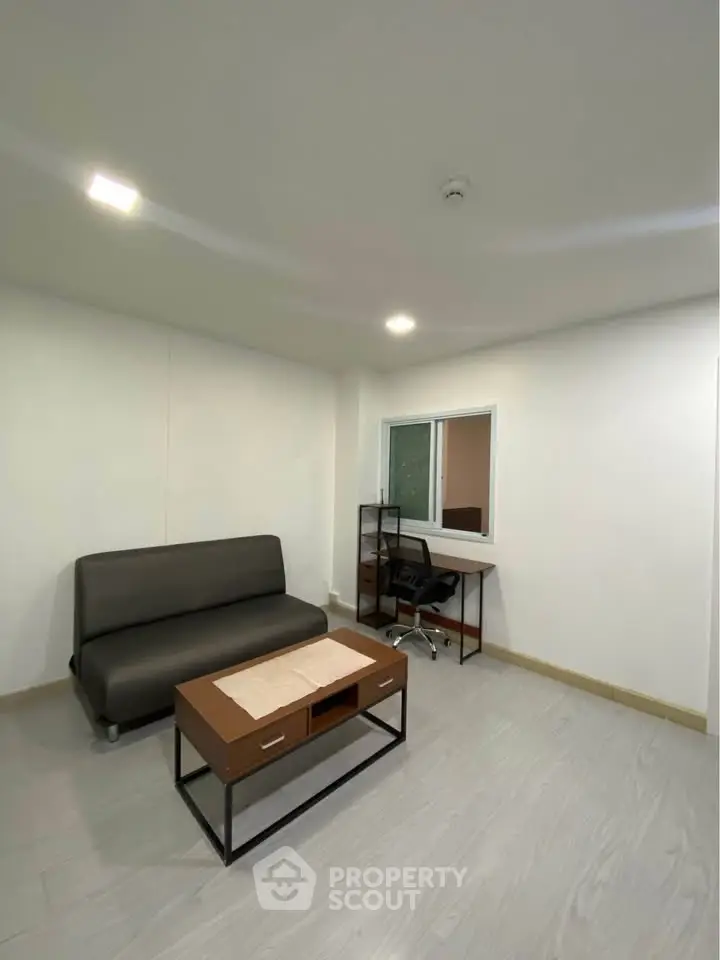 Modern minimalist living room with sleek sofa and stylish desk, perfect for urban living.