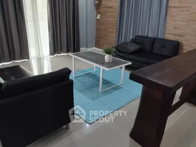 Modern living room with sleek black sofas, wooden accents, and a stylish coffee table on a blue rug.