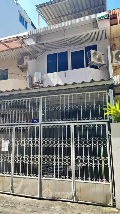 Charming urban townhouse with gated entrance and air conditioning units, perfect for city living.