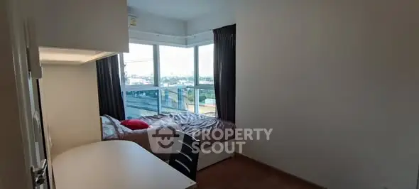 Cozy bedroom with large windows offering a stunning city view, perfect for relaxation and inspiration.