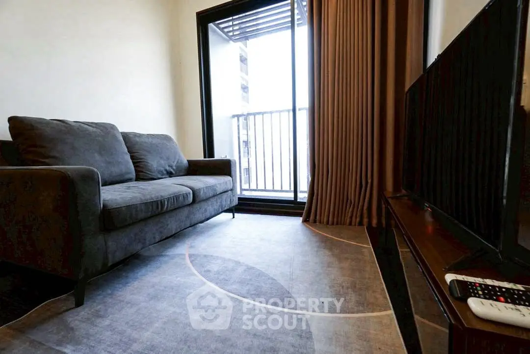 Cozy living room with plush sofa and balcony access, perfect for relaxation and entertainment.