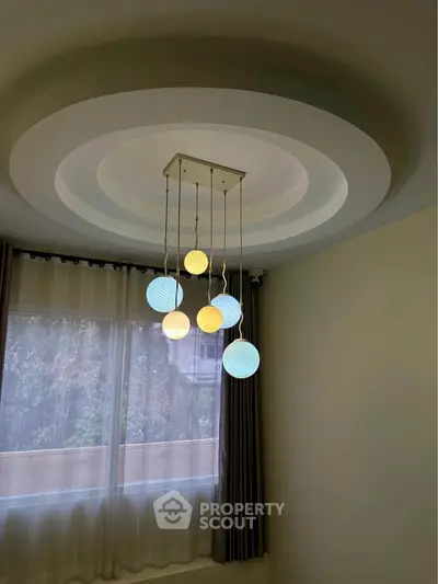 Elegant modern living room with unique ceiling light fixture and large window with curtains.