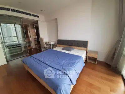 Spacious modern bedroom with wooden flooring and stylish furniture