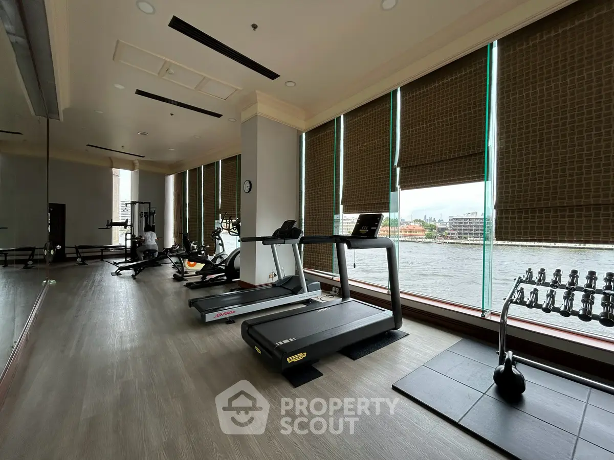 Spacious gym with river view, featuring modern exercise equipment and large windows for natural light.
