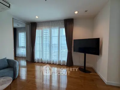 Spacious living room with floor-to-ceiling windows and modern TV setup in a high-rise apartment.