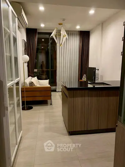 Modern living room with elegant decor and open kitchen layout, featuring stylish lighting and cozy seating area.