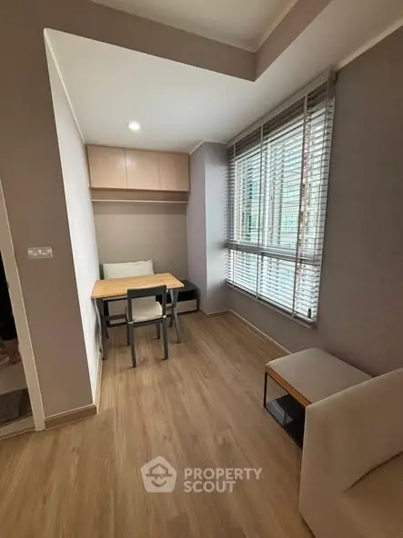 Cozy study nook with modern desk and chair, large window with blinds, and wooden flooring.