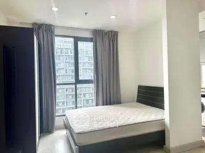 Modern bedroom with large window and city view in high-rise apartment