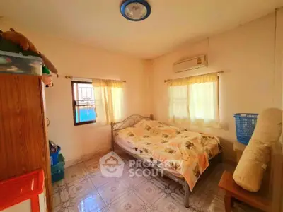 Cozy sunlit bedroom with ample natural light, air conditioning, and tiled flooring, perfect for comfortable living.