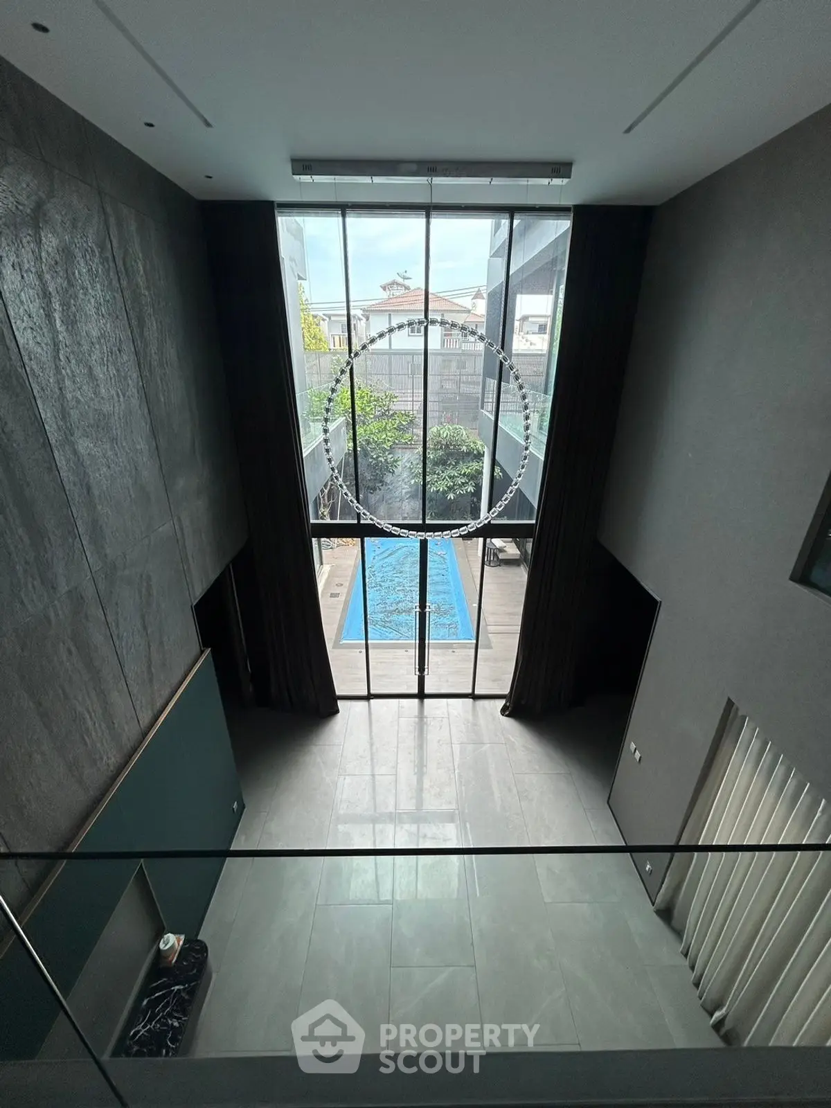 Luxurious modern home with stunning pool view through floor-to-ceiling windows.