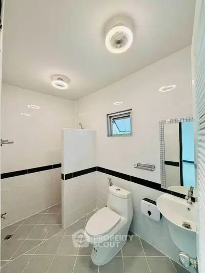Modern bathroom with sleek fixtures and minimalist design, featuring a walk-in shower and contemporary lighting.