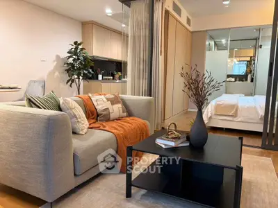 Modern open-plan living room with cozy sofa and stylish decor adjacent to a sleek kitchen and bedroom.