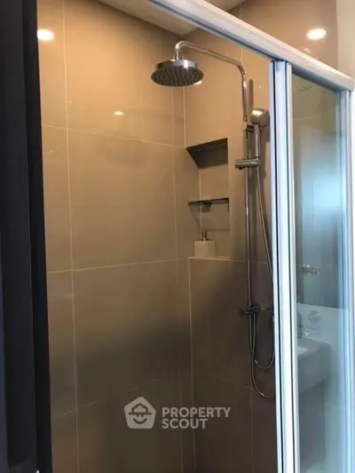 Modern bathroom with sleek shower and glass door in contemporary apartment.