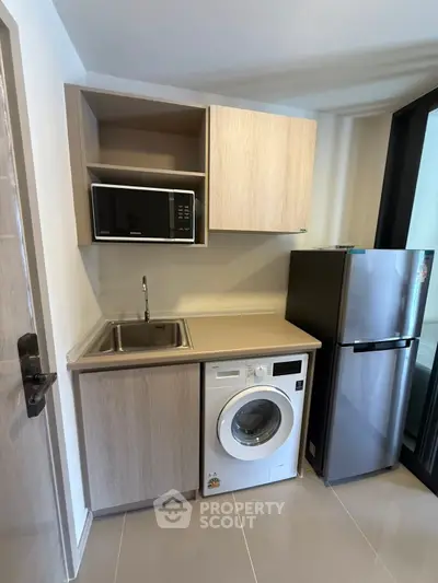Compact kitchen with modern appliances including fridge, microwave, and washing machine.