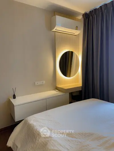 Modern bedroom with stylish decor, featuring a cozy bed, elegant mirror, and air conditioning for comfort.
