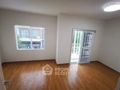 Spacious room with wooden flooring and large windows for natural light