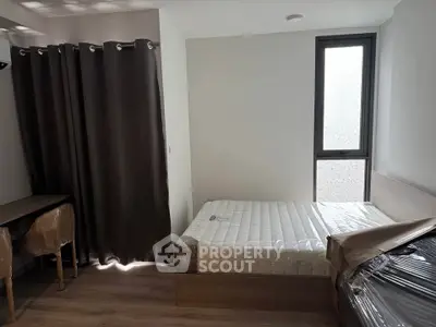 Modern bedroom with natural light, featuring a bed, desk, and floor-to-ceiling window.