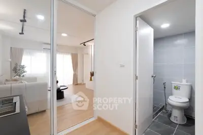 Modern apartment interior with living room and bathroom, featuring sleek design and natural light.