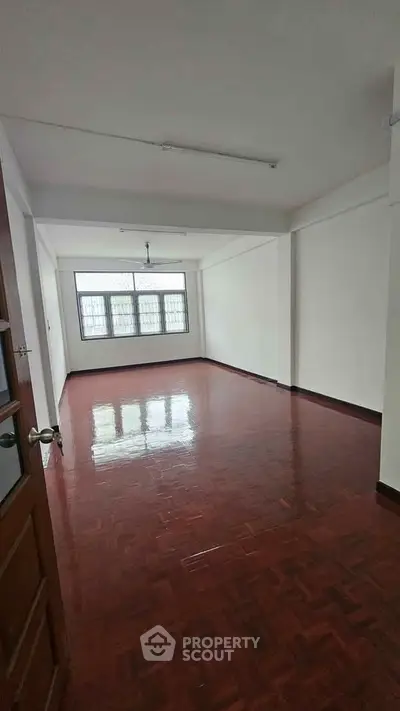 Spacious empty room with polished wooden floors and large windows