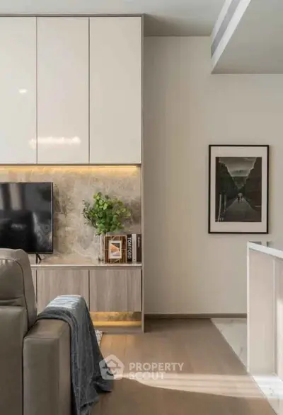 Modern living room with sleek cabinetry and stylish decor, featuring a wall-mounted TV and elegant artwork.