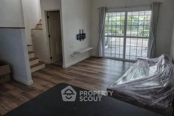 Spacious living room with large windows and wooden flooring, perfect for modern living.