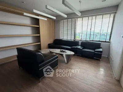 Modern living room with sleek black leather sofas and large window view.