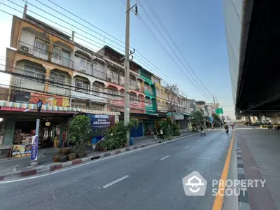 Charming street view of colorful multi-story buildings with shops and greenery, ideal for urban living.