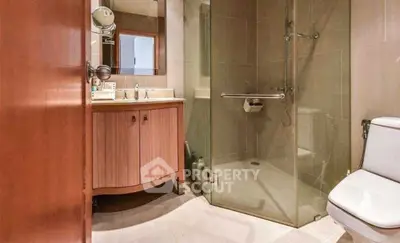 Modern bathroom with glass shower and elegant wooden vanity.