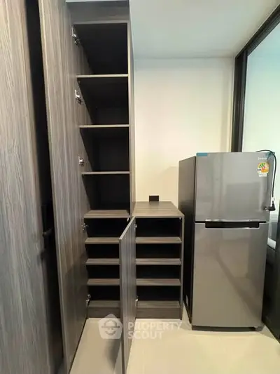 Modern kitchen with sleek cabinetry and stainless steel fridge in a contemporary apartment.