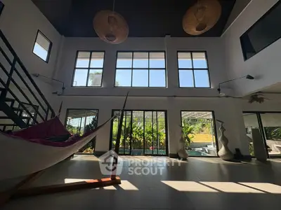 Spacious modern living room with high ceilings and large windows overlooking lush garden.