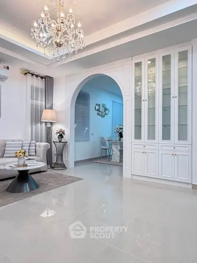 Elegant living room with chandelier, archway, and built-in cabinets in a luxurious home.