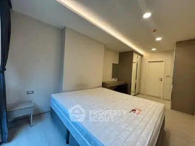 Spacious bedroom with modern design and ample natural light, featuring a comfortable bed and sleek furnishings.