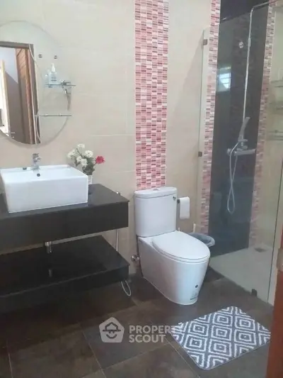 Modern bathroom with glass shower, stylish sink, and decorative tiles.