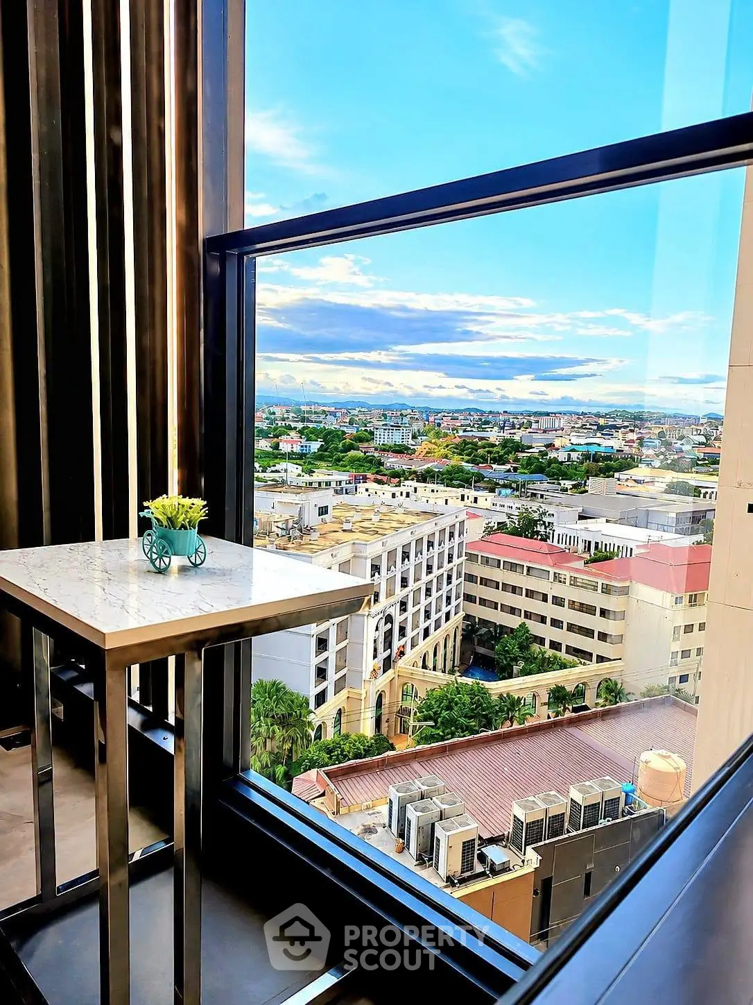 Stunning high-rise view from a modern balcony overlooking the cityscape with clear blue skies.