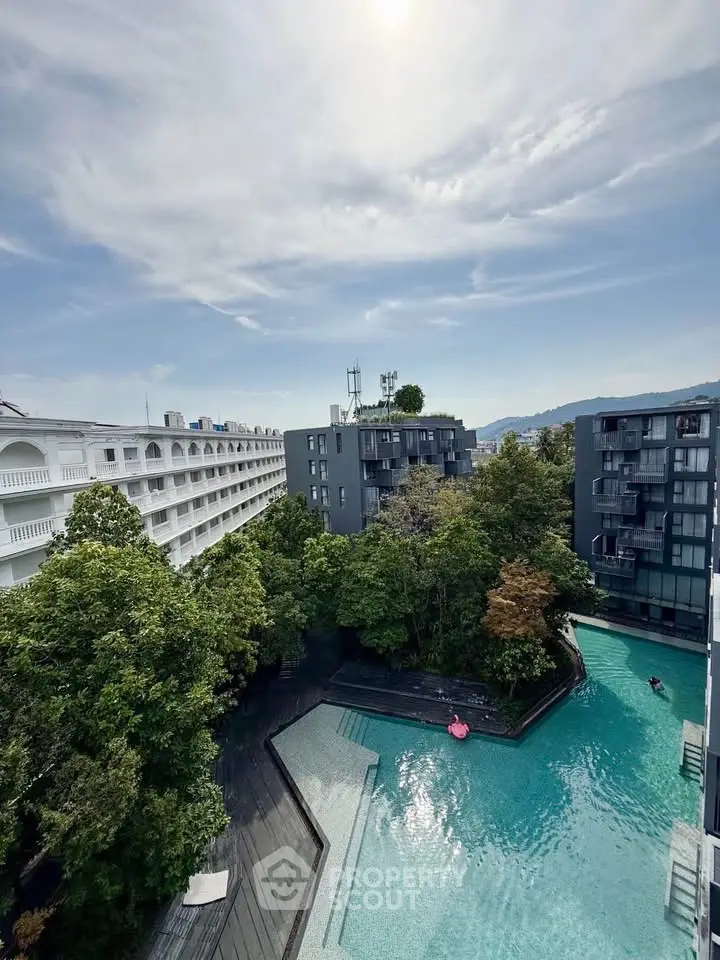 Stunning aerial view of modern apartment complex with lush greenery and inviting swimming pool.